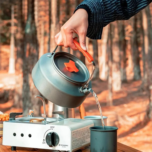 bouilloir tenue par une personne servant eau chaude dans tasse en camping