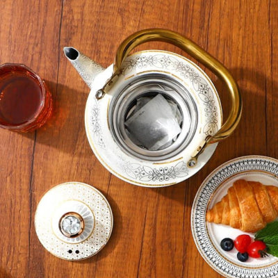 bouilloire et theiere utilise au petit dejeuner croissant et tasse de the a cote