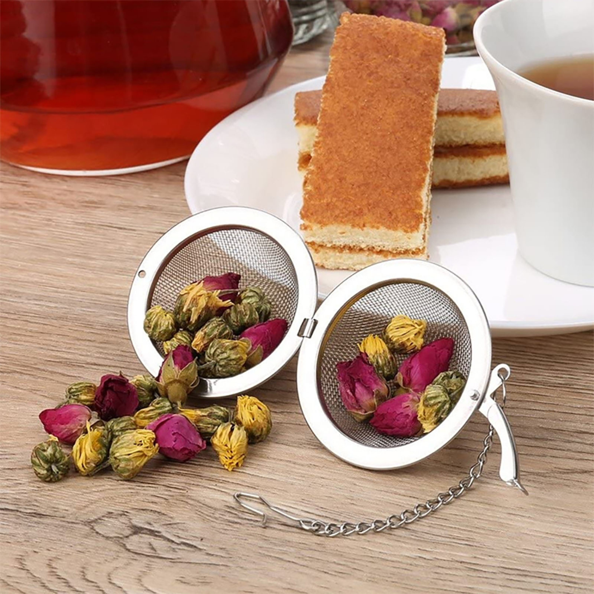 boule à thé ouvert remplit thé fleur séché à coté cake tasse thé