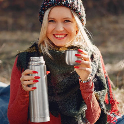 bouteille inox isotherme grise utilise par femme avec bouchon tasse