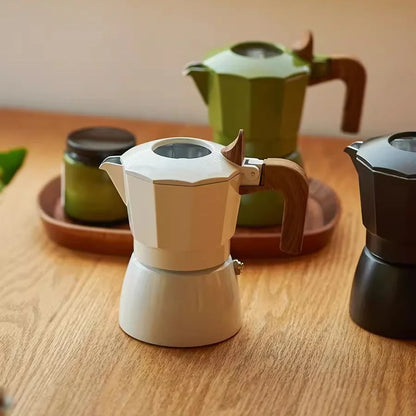 cafetiere italienne moka verte noire blanc sur plateau et bois marron