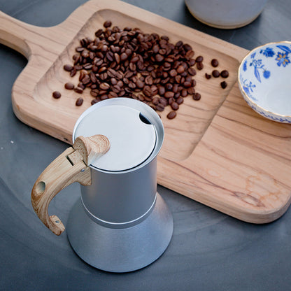 cafetières italiennes sur table planche bois tasse et grain de cafe en decor