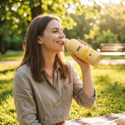 femme buvant avec isotherme bouteille jaune au parc