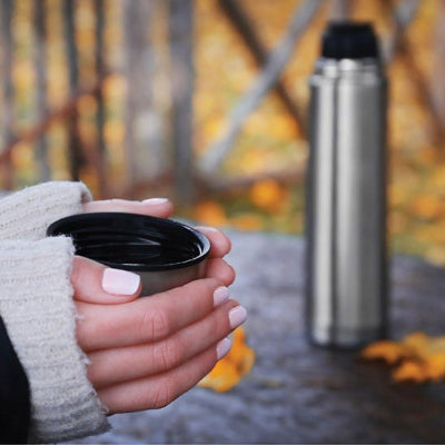 femme tenant bouchon tasse bouteille inox isotherme a cote