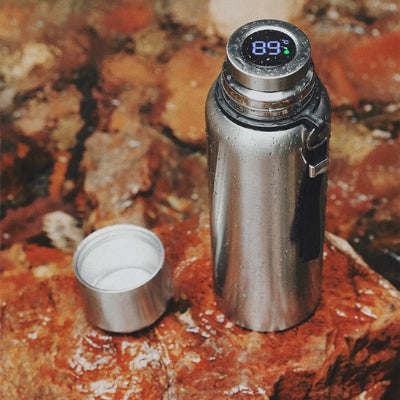 gourde isotherme inox avec affichage temperature ouvert sur un rocher