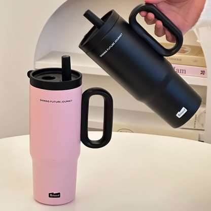 gourde isotherme rose sur table et noire tenue par une personne