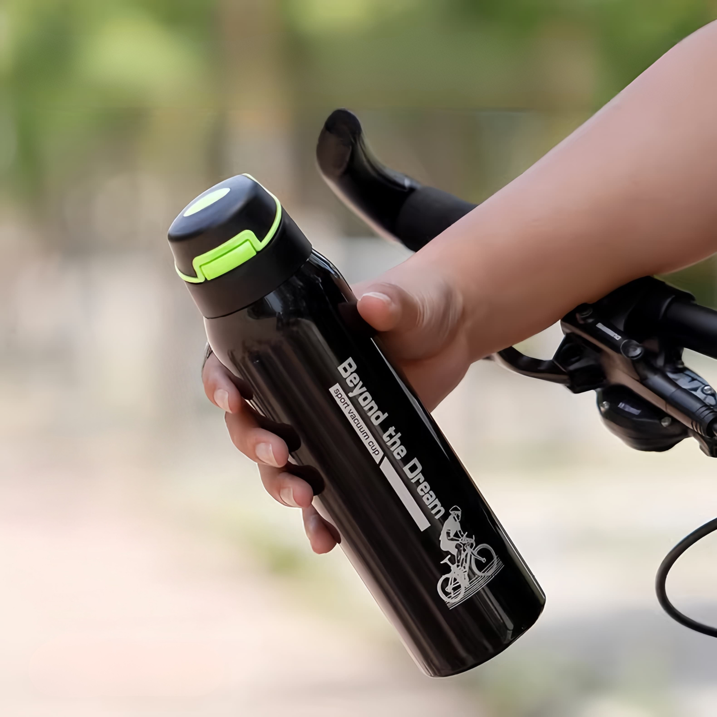 gourde isotherme velo noire tenue par un cycliste