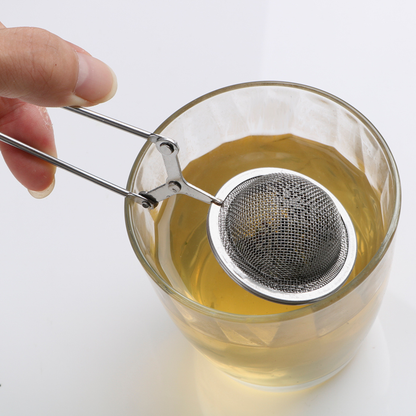 infuseur de the tenue par une personne dans un verre de the