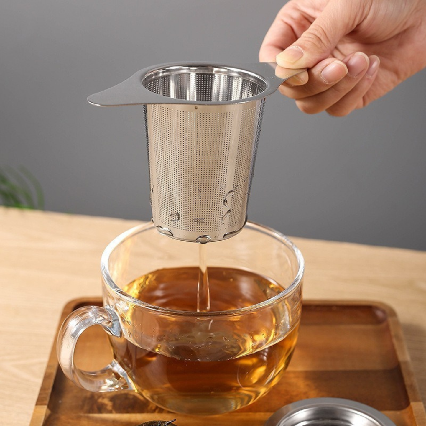 infuseur pour théière utilise par une personne tasse the sur planche bois