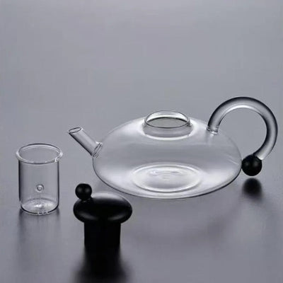 infuseur-theiere-sur-table-grise-couvert-noire-et-infuseur-a-cote
