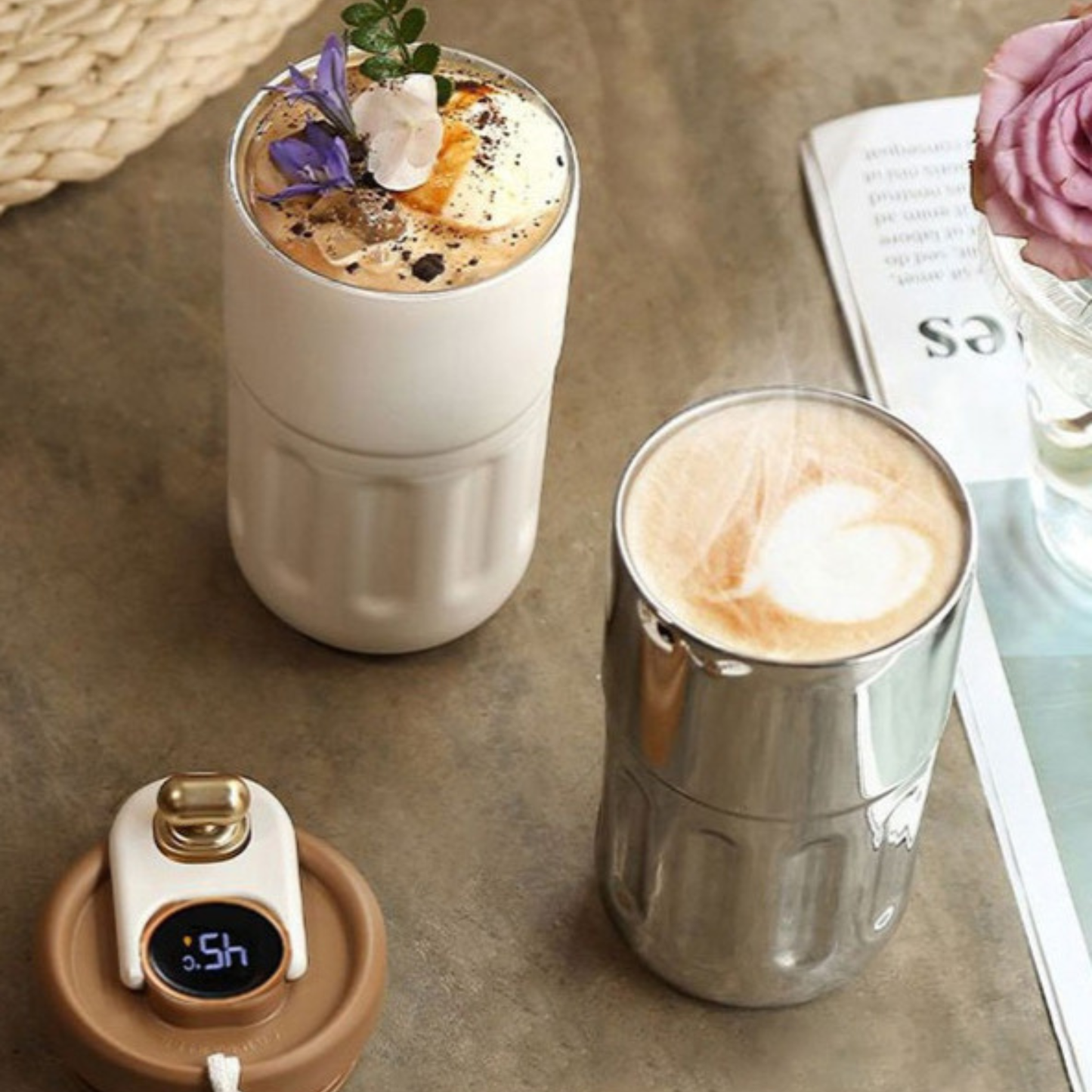 mug café isotherme blanc et argentée remplit de café sur table fleur et magazine à cote