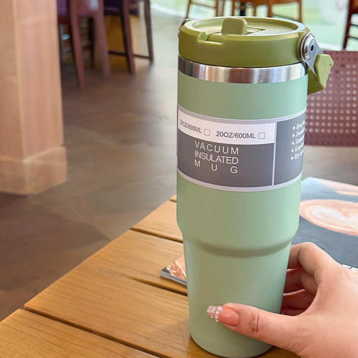 mug isotherme de voyage vert pose sur table tenue par une femme