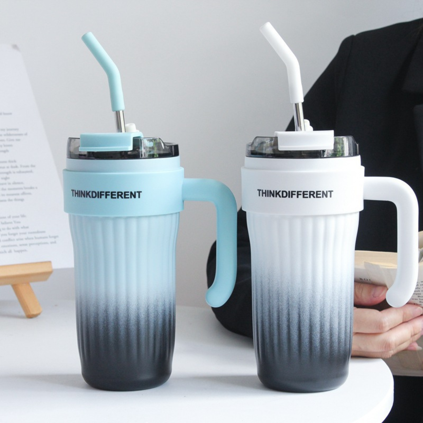 mug isotherme paille blanc degrade noir et bleu degrade noir sur table une personne a cote