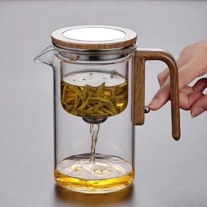 personne drainant theiere en verre sur table bois