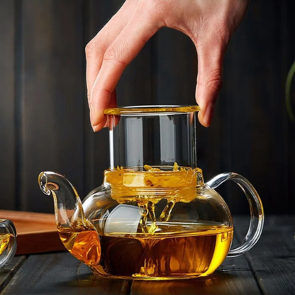 personne enlevant infuseur du théière en verre transparent remplit thé