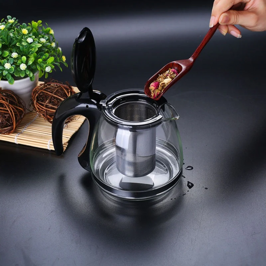 personne mettant thé dans théière en verre design