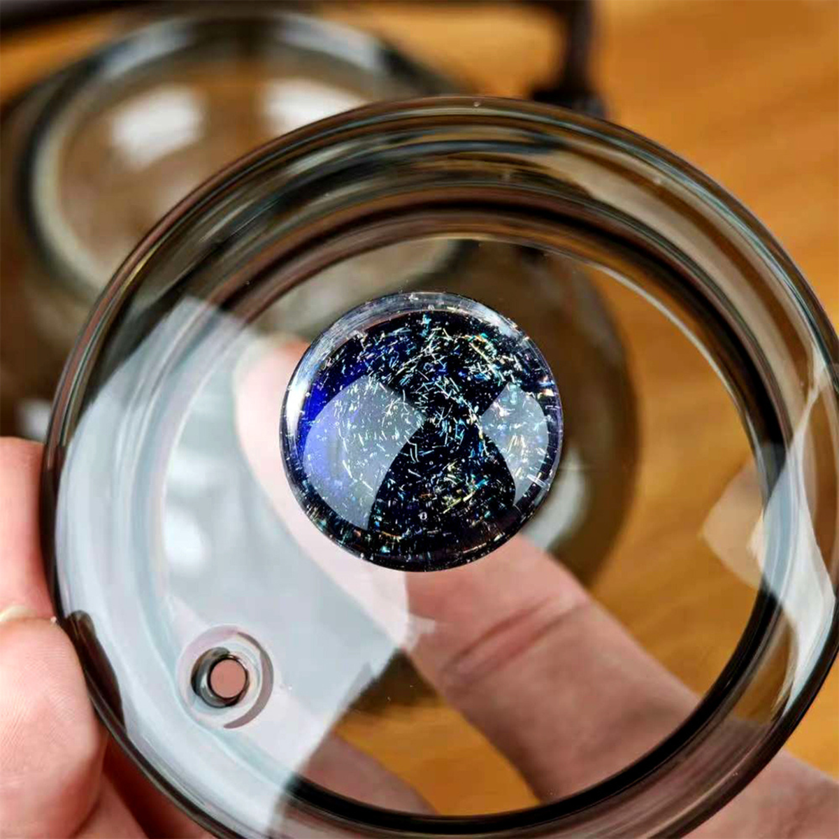 personne montrant couvercle théière en verre avec infuseur 