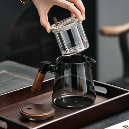 personne montrant infuseur dans théière en verre et bois