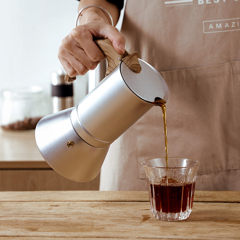 personne servant cafe avec cafetières italiennes sur table bois