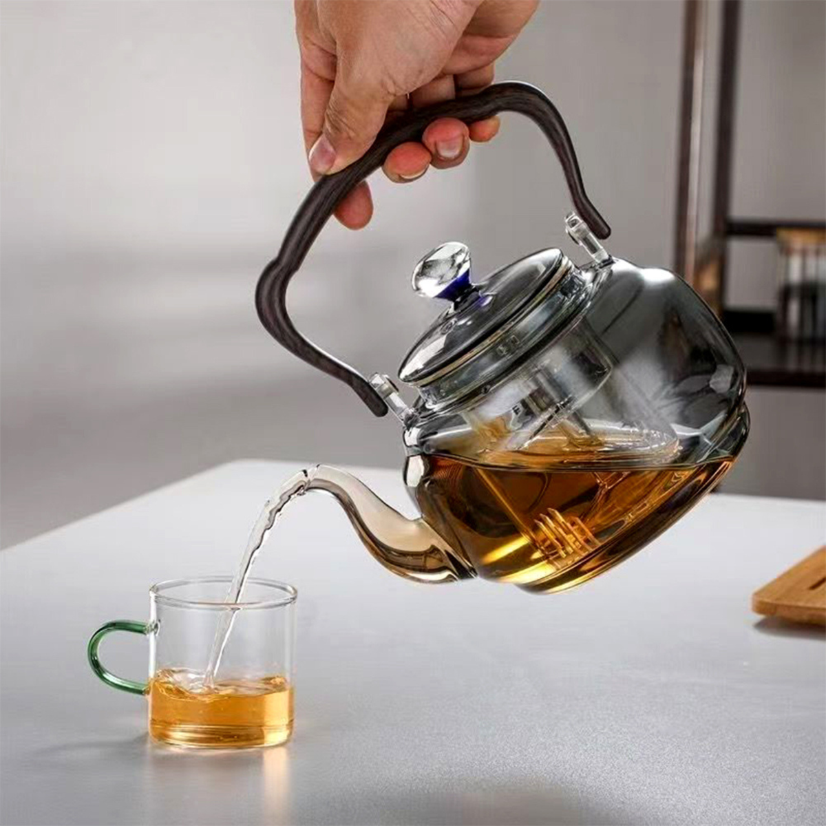 personne servant thé avec théière en verre avec infuseur 