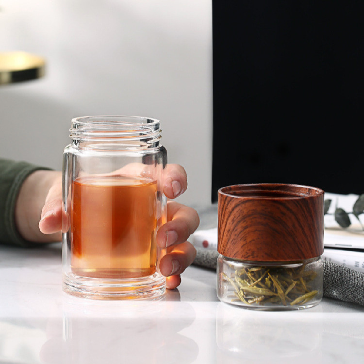 personne tenant bouteille théière en verre marron ouverte au bureau