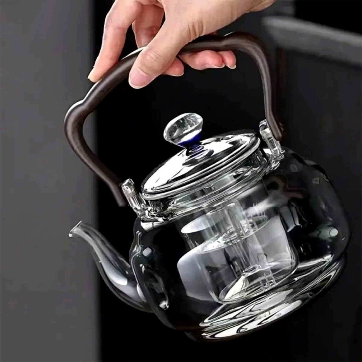 personne tenant  théière en verre avec infuseur  vide