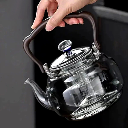 personne tenant  théière en verre avec infuseur  vide