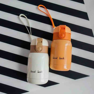 petite bouteille isotherme orange et beige sur nappe rayee