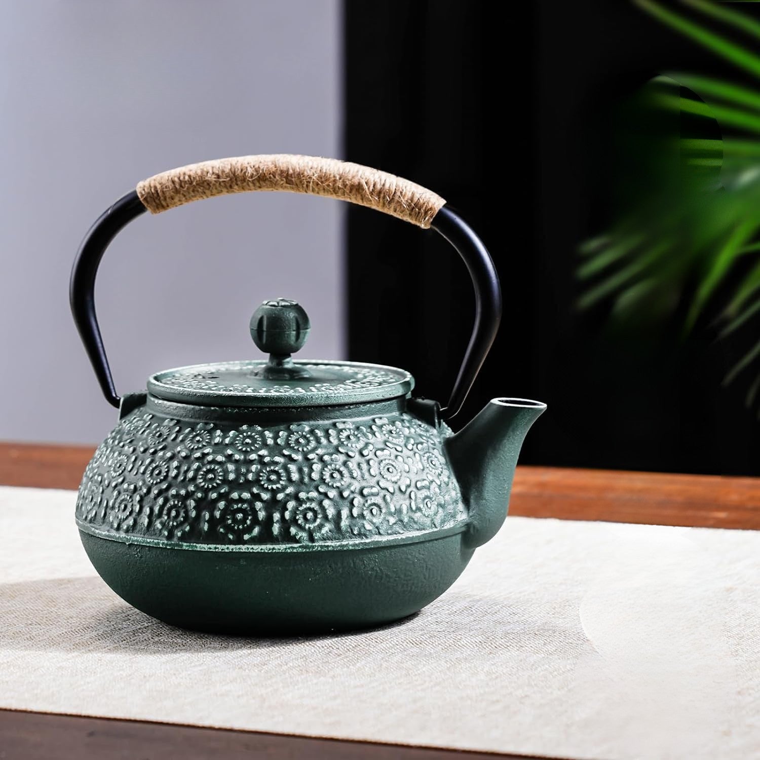 theiere en fonte de couleur verte sur table nappe marron