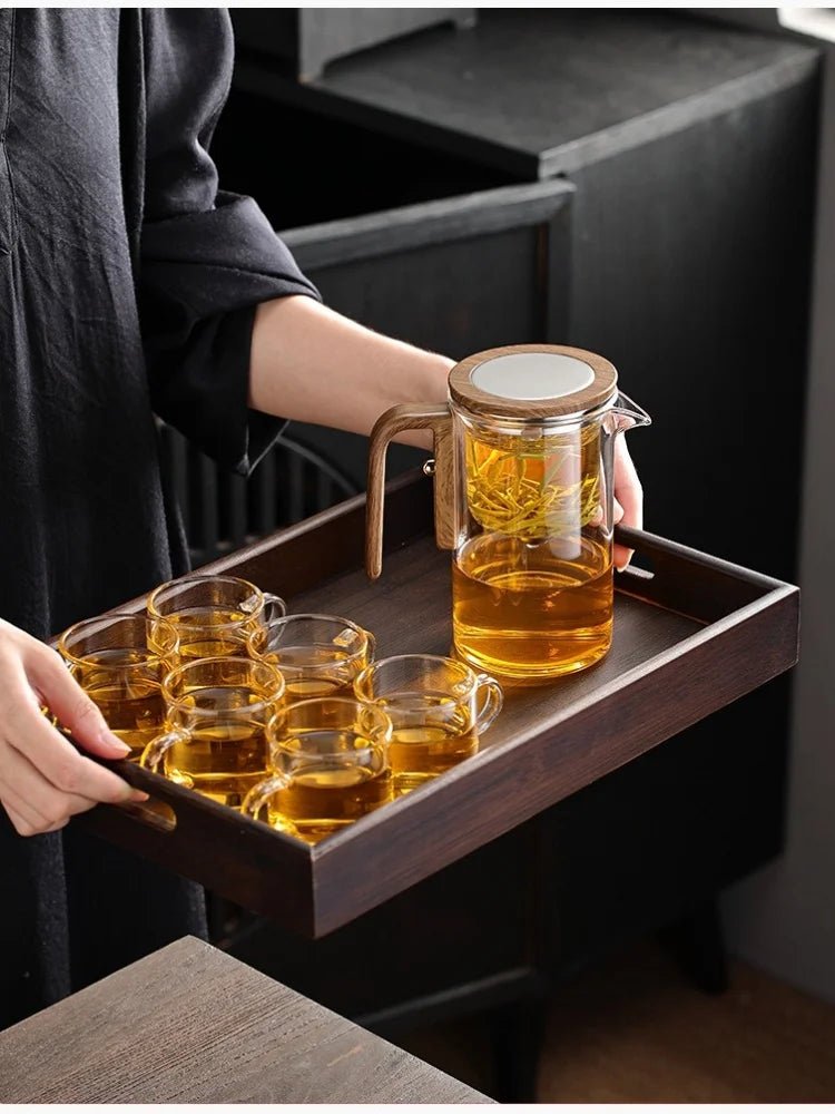 personne tenant plateau bois avec theiere en verre avec tasse the pour servir