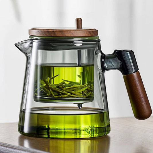 théière en verre et bois replit de thé sur table