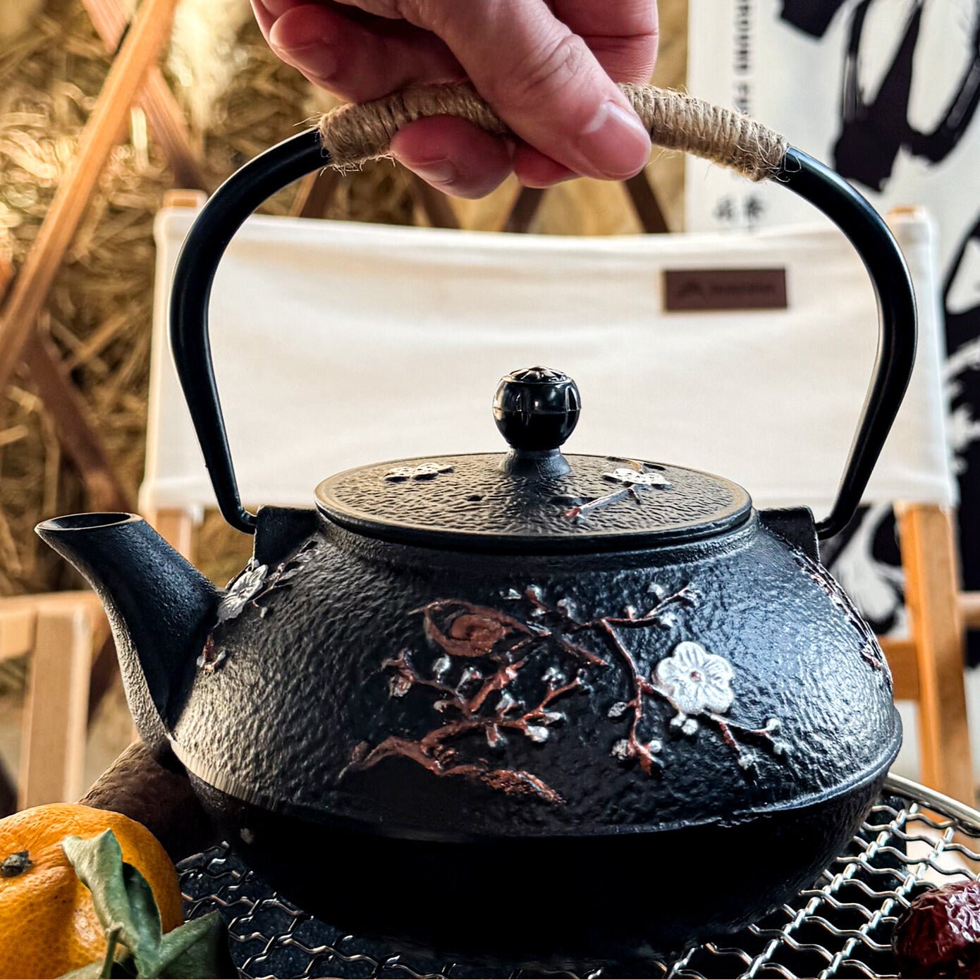 theiere japonaise sur feu avec grillage noir fruit a cote