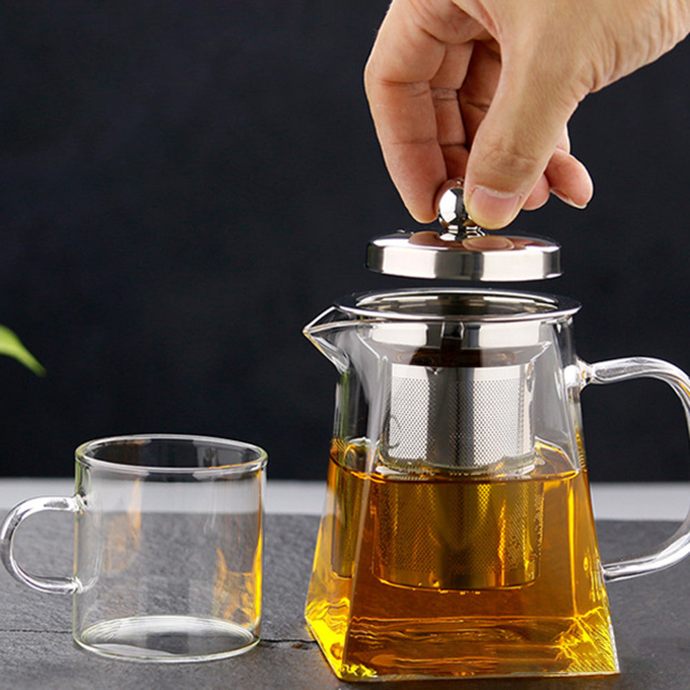 theiere verre remplit de the tasse verre a cote personne tenant couvercle pres a servir