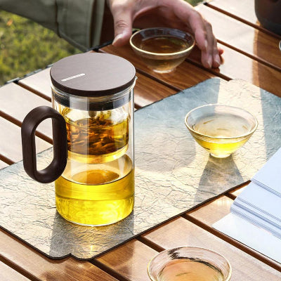 theiere verre sur table bois marron une personne savourant sa tasse the