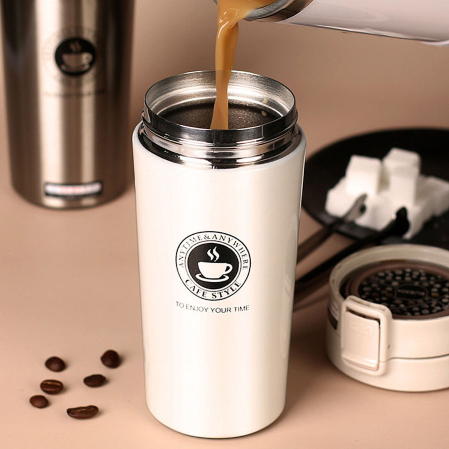une personne remplissant de cafe son mug isotherme inox grains cafe sucre a cote